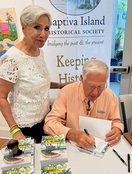 As his wife Angie watches, Tony Lapi signs copies of his book Tales of an Island Innkeeper